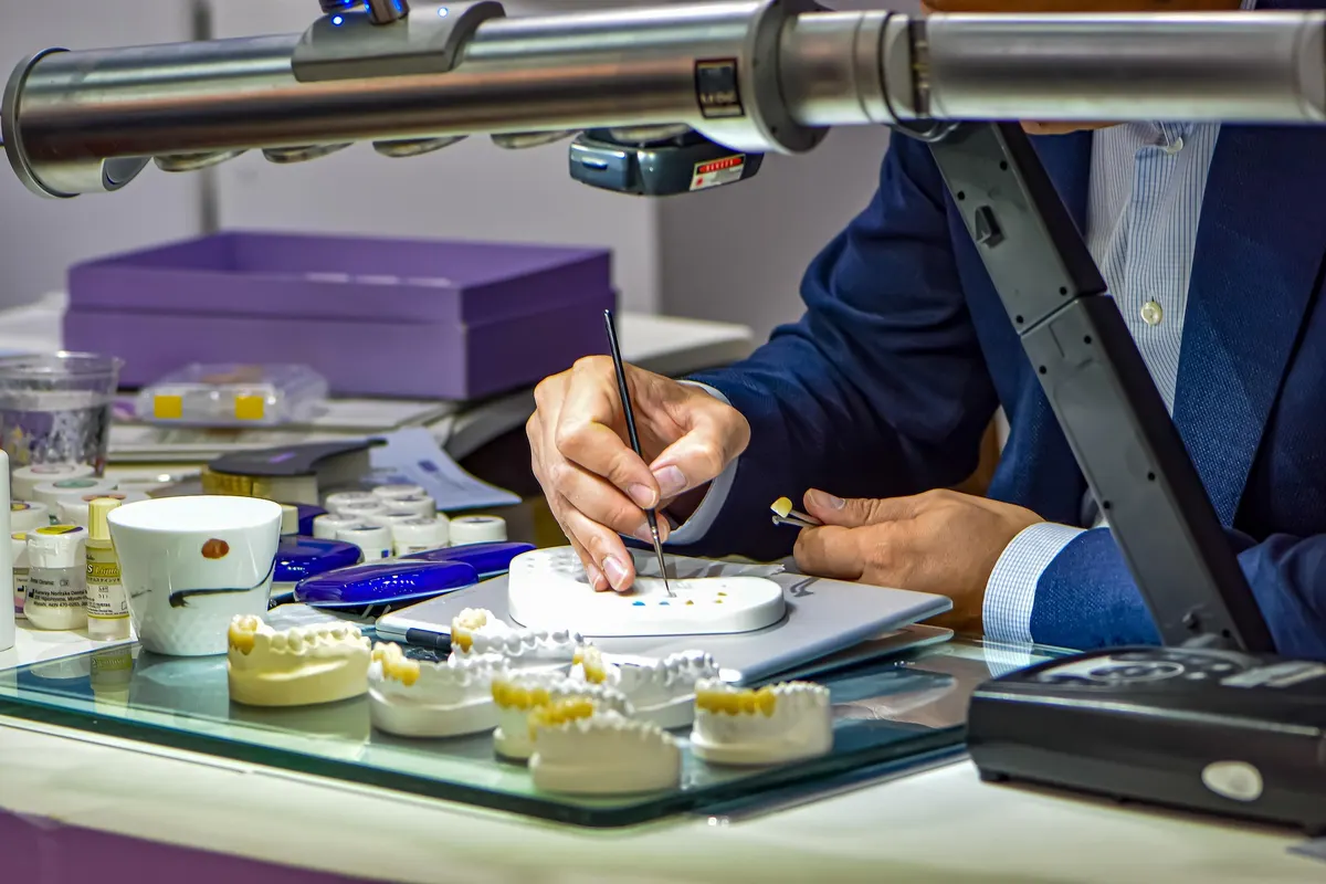 Dental technician working on dental models at a lab bench